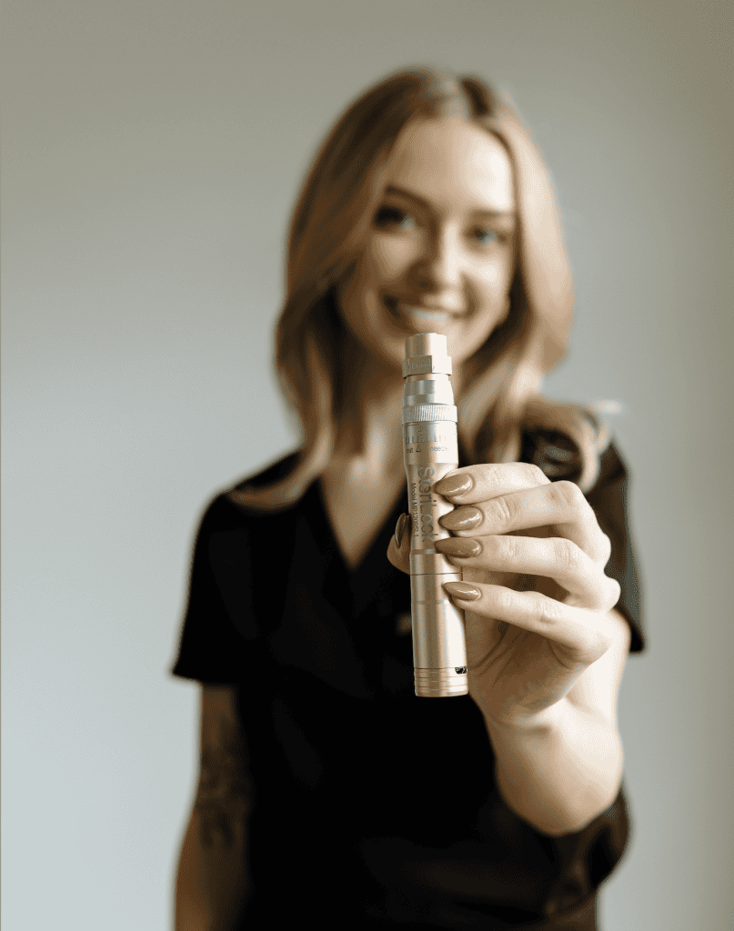 Esthetician holding a microneedling pen before a skincare treatment.